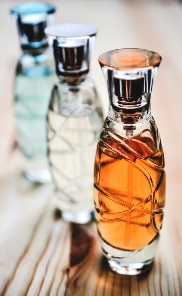 Tre flaconi di profumo in vetro affiancati su superficie di legno