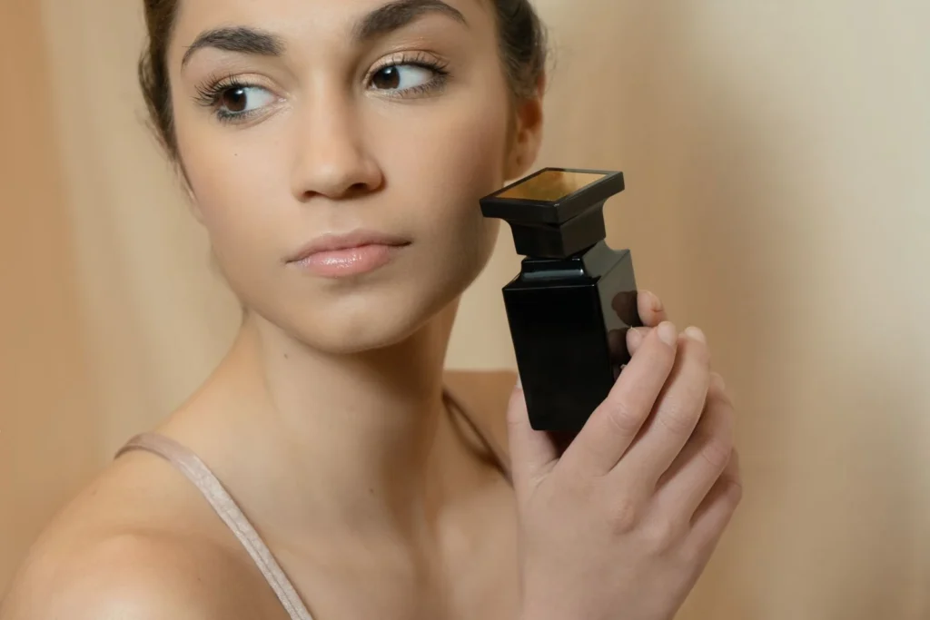 Donna che tiene in mano un flacone di profumo pronta ad applicarlo sul polso