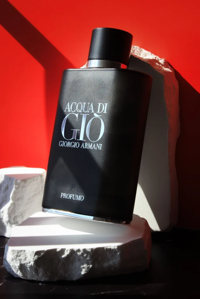 Flacone di profumo nero elegante su sfondo rosso, atmosfera calda e ambrata