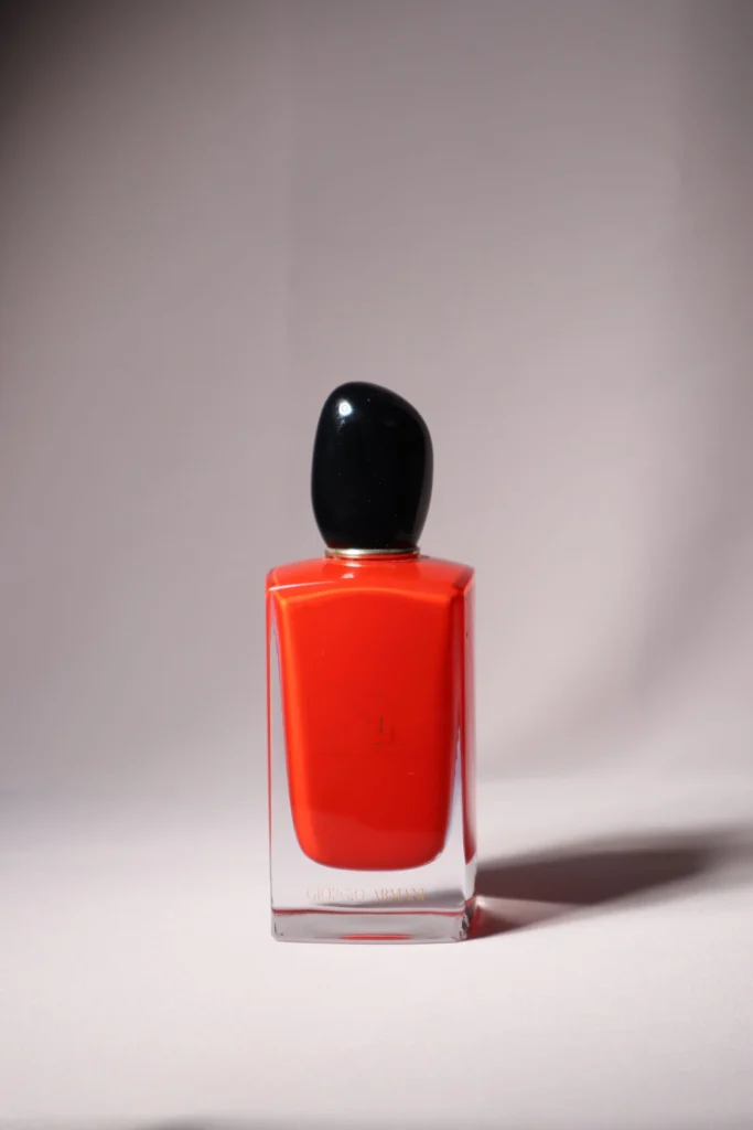 Flacone di profumo rosso su sfondo minimal, dettaglio del vetro
