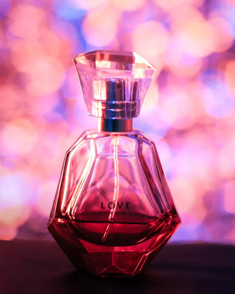 Primo piano di un flacone di profumo rosa con la scritta Love, stile giovane e dolce